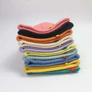 Bunter Stapel gestrickter Kinder-Beanies in zehn Farben mit dekorativen Webetiketten am Rand