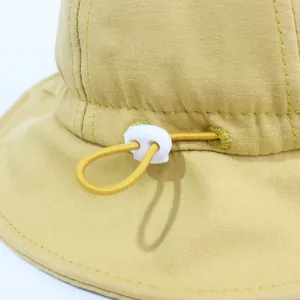 Dettaglio cappello da sole giallo con coulisse regolabile e fibbia a molla in plastica