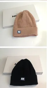Dettaglio della trama a maglia intrecciata su berretti invernali beige e neri