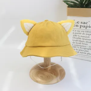 Détail du bob bébé en velours côtelé jaune avec oreilles 3D et mentonnière blanche