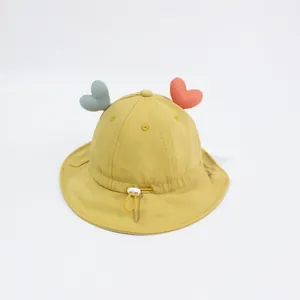 Dettaglio cappello a secchiello giallo per neonati con cuori e cordoncino regolabile
