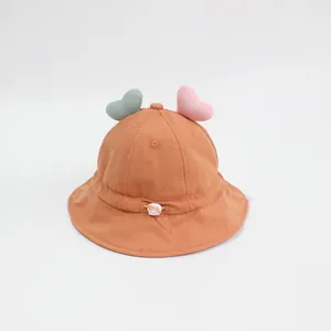 Dettaglio di un cappello a secchiello per neonati con cuori morbidi e cordino regolabile