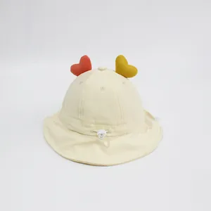 Dettaglio cappello sole neonato con cuori di peluche e coulisse regolabile sotto il mento
