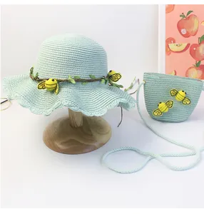 Dettaglio cappello di paglia verde menta e borsa con ornamenti di api e foglie