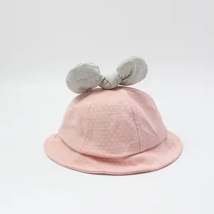 Pink polka dot cotton baby sun hat with a grey bow decoration on a clean white background