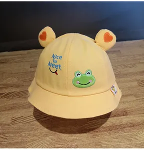 Dettaglio cappello pescatore giallo per bambini con ricamo rana e orecchie a cuore