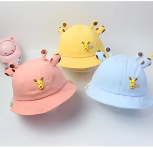 Detalle de sombreros de pescador infantiles con diseño de jirafa en rosa, amarillo y azul