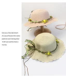 Dettaglio di cappelli di paglia a tesa ondulata con viti di fiori e ape in rosa e beige