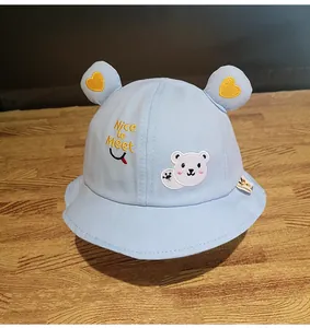 Dettaglio cappello a secchiello blu chiaro per neonati con ricamo orso e orecchie
