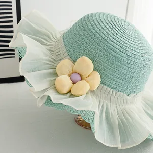 Detail of mint green straw hat with pleated tulle brim and soft fabric flower accent