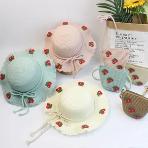 Close-up of kids straw hats and matching cherry bags in four soft summer pastel colors