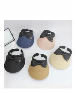 Detail showing wide brim straw sun hats with black bows and golden M logo in five colors