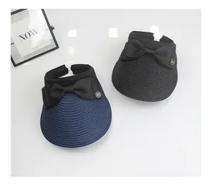 Detail view of woven straw sun visors with elegant bows and metallic M accents
