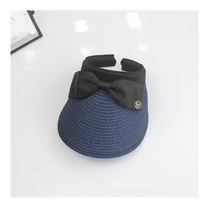 Detail of navy straw sun hat brim with elegant black bow and golden M metal buckle