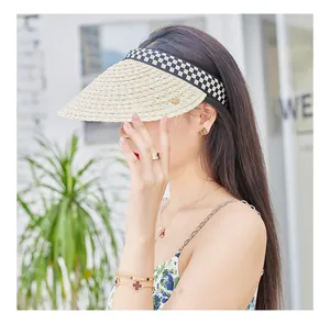 Detail of raffia sun visor with checkerboard ribbon edge and woven texture on model