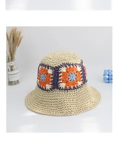 Detail of hand-woven straw sun hat showing colorful crochet flower patterns and texture