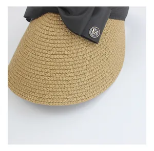 Detailed macro view of woven straw visor texture with black ribbon and metal M letter buckle