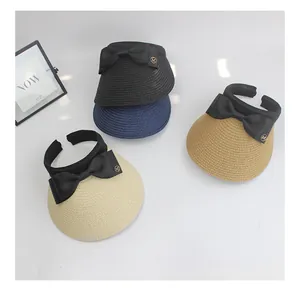 Detail of summer straw sun hats in four colors with large bows and gold M emblems