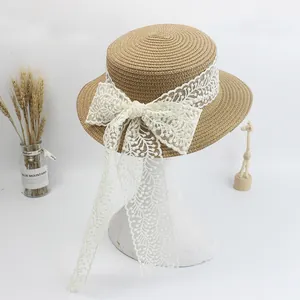 Beige straw boater hat with white lace bow and ribbons on a model head for summer