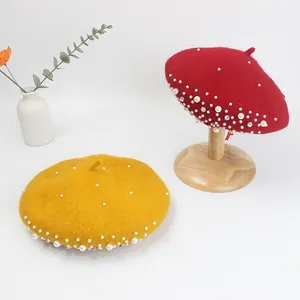 Detail of red and yellow wool berets with pearls and rhinestones on a wooden stand