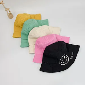 Detail of five colorful cotton bucket hats with smile embroidery and frayed brim texture