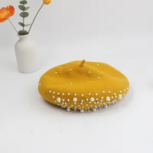 Detail of yellow wool beret featuring elegant white pearls and sparkling rhinestones
