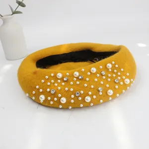 Close-up of yellow wool beret featuring elegant hand-stitched pearls and shiny rhinestones