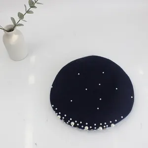 Detail of navy wool beret with white pearls and rhinestones on white background