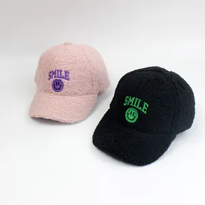 Detailansicht weicher Lammwoll-Baseballkappen in Rosa und Schwarz mit Smile-Stickerei