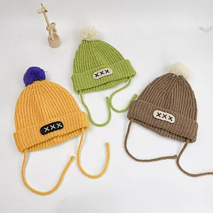 Kids warm knit beanies with pom poms and earflaps in ginger, green and brown colors
