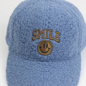 Nahaufnahme der blauen Lammwoll-Kappe mit SMILE-Schriftzug und Smiley-Stickerei