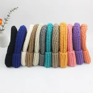 Détail de bonnets en grosse maille colorés soigneusement disposés sur une surface blanche