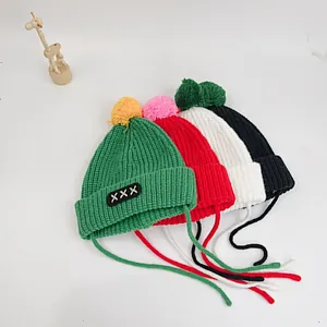 Knit kids' warm winter hats with fluffy pom-poms and earflaps in multiple colors