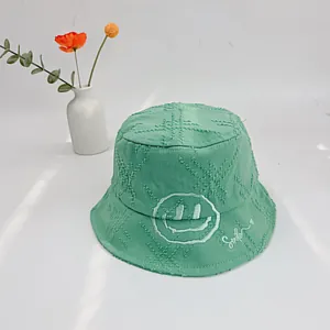 Detail of mint green cotton bucket hat with smile embroidery and frayed edge design