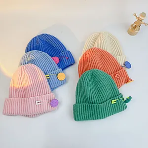Detailed knit texture of solid color kids' beanies with cute smiley face safety pins
