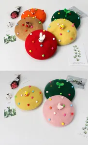 Detail of handmade wool felt beret featuring cute 3D animal icons and colorful pom-poms