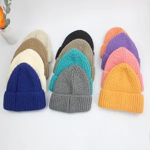 Mise à plat de bonnets en maille épaisse en bleu, crème, kaki et gris sur fond blanc