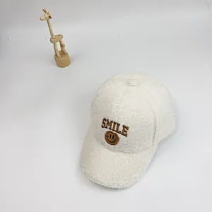 Detail der weißen Teddyfell-Baseballcap mit brauner SMILE-Stickerei und Smiley-Gesicht