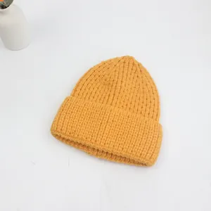 Détail d'un bonnet en maille épaisse jaune gingembre avec texture côtelée et large revers