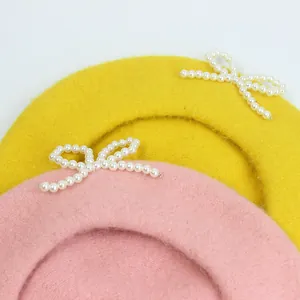 Detail der Wollbaskenmütze mit dekorativer Perle-Schleife in Pink und Gelb