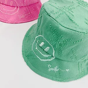 Detail of distressed cotton bucket hat featuring smiley face embroidery and frayed edges