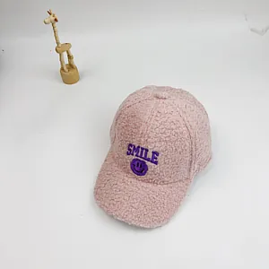 Detailansicht der rosa Teddy-Fleece-Kappe mit lila SMILE-Stickerei und Smiley-Symbol