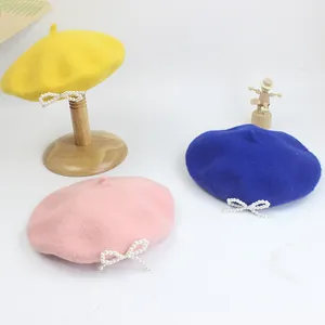 Detailaufnahme der Wollbaskenmützen mit Perlenbogen in Gelb, Blau und Rosa für Kinder