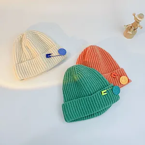 Detailed knit texture of children's beanies with decorative safety pin and smile charms