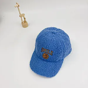 Detailansicht der blauen Lammwoll-Kappe mit gelbem Smiley-Patch und Smile-Stickerei