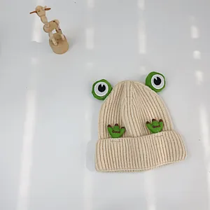 Detail einer beige gerippten Kinder-Strickmütze mit 3D-Froschaugen und Good-Stickerei