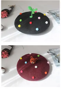 Detalle de boinas de fieltro de lana con lindos diseños 3D de brote y oso en negro y granate