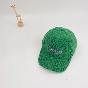 Détail de la casquette verte en sherpa avec broderie Chaser violette et texture pelucheuse
