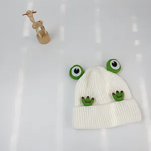 Detailansicht der weißen Baby-Strickmütze mit 3D-Froschaugen und Good-Stickerei