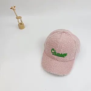 Détail de la texture en laine d'agneau rose et broderie Chaser verte sur la casquette